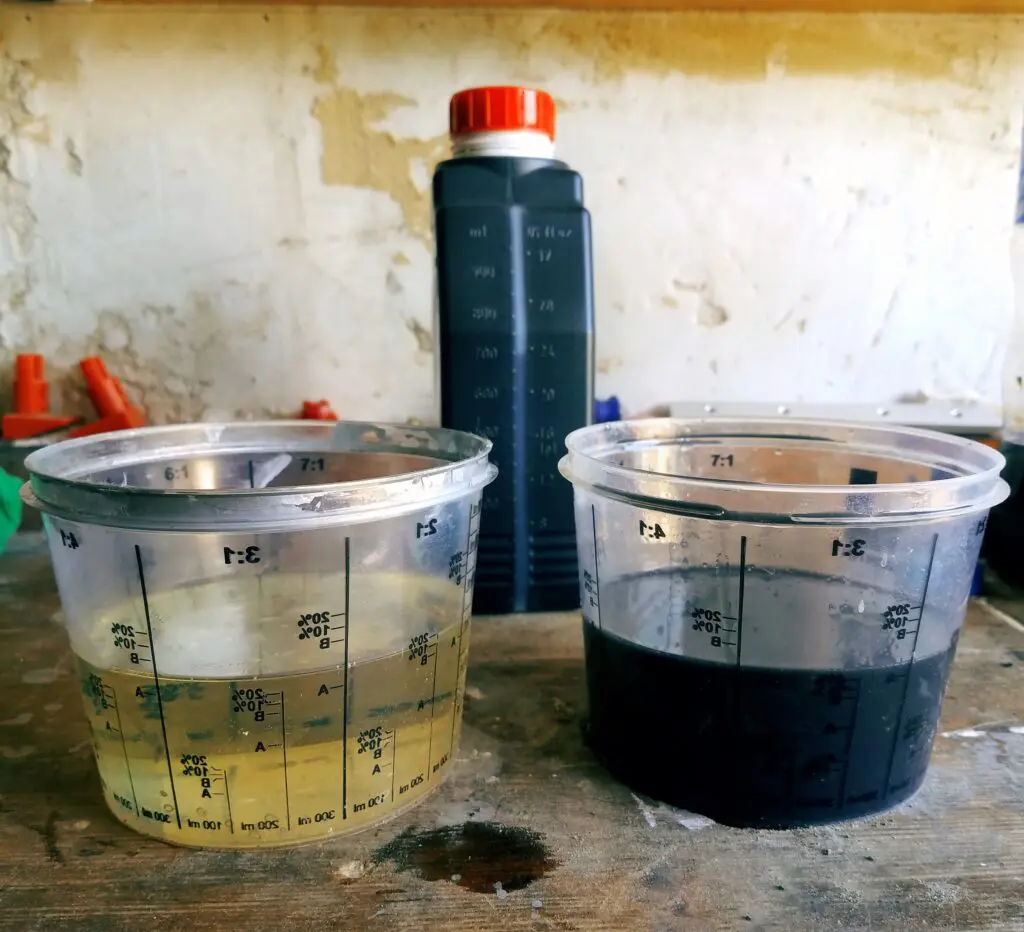Two measuring glasses with clean and used engine oil standing on the table against the background of the canister