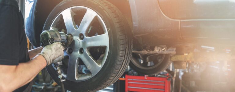 car mechanic screwing the wheel at auto repair garage