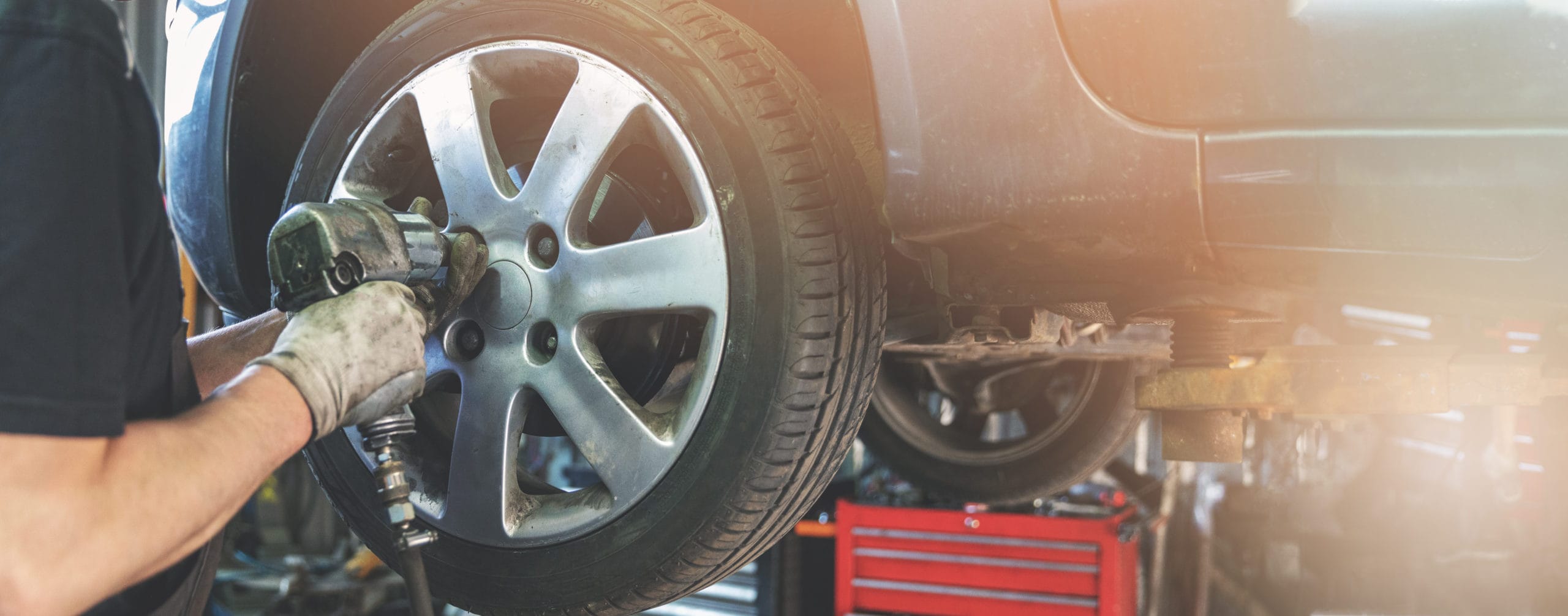 car mechanic screwing the wheel at auto repair garage