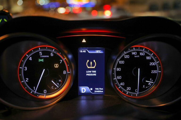 A lit up car dashboard display with the low tire pressure indicator light on and low tire pressure warning in the center.