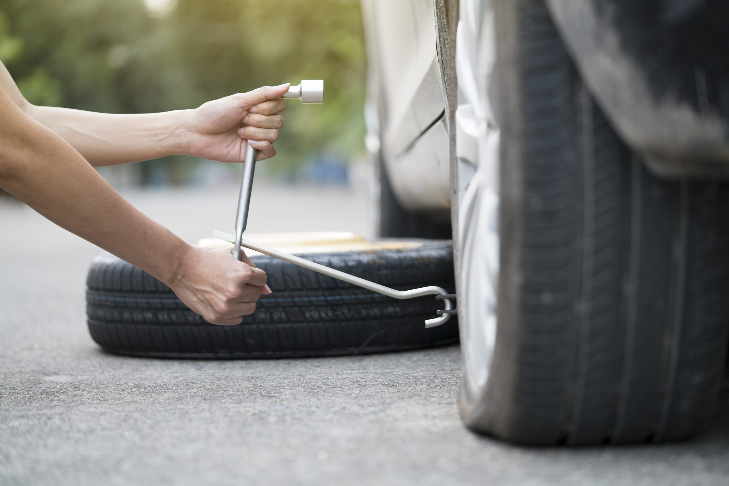 Woman changing wheel on a roadside.