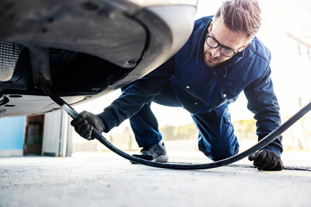 An auto-mechanic checking on car exhaust gases on a technical service.