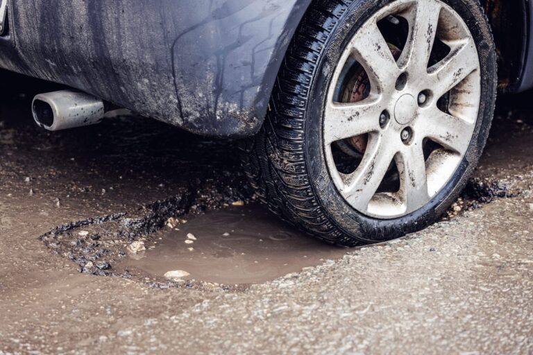 Closeup photo of a dirty car tire in filthy pothole