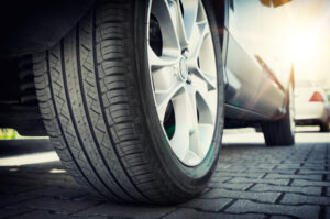 Dramatic closeup photo of a car tire of a brick pavement with a lens flare coming down on the car