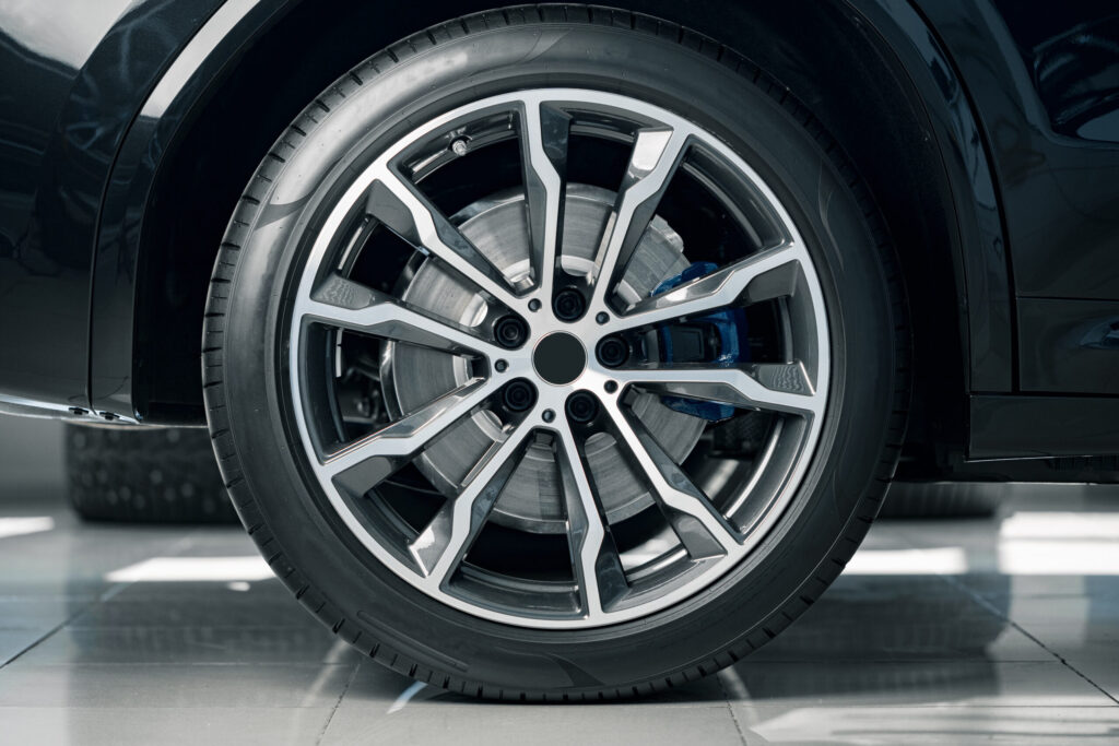 Closeup photo a perpendicular shot of a tire on a car on tile in a well lit room