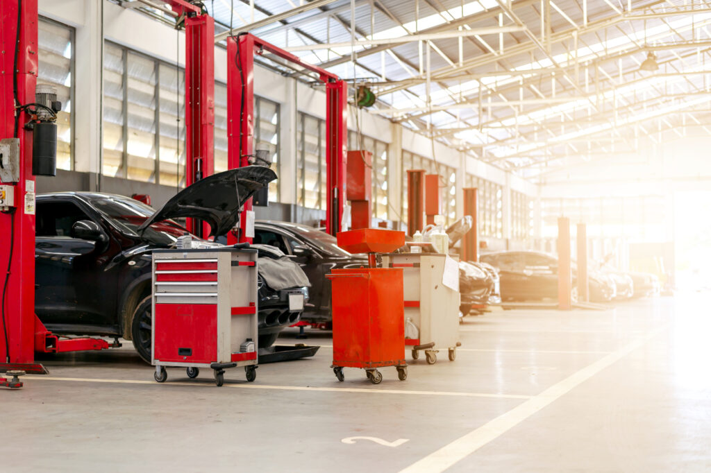 Inside auto repair shop with car hoods open.