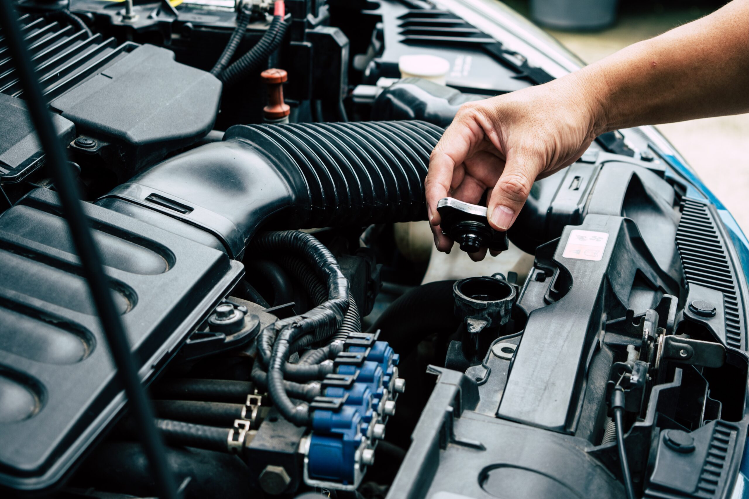 Mechanic's hand checking a car's radiator in a Telle Tire & Auto Center