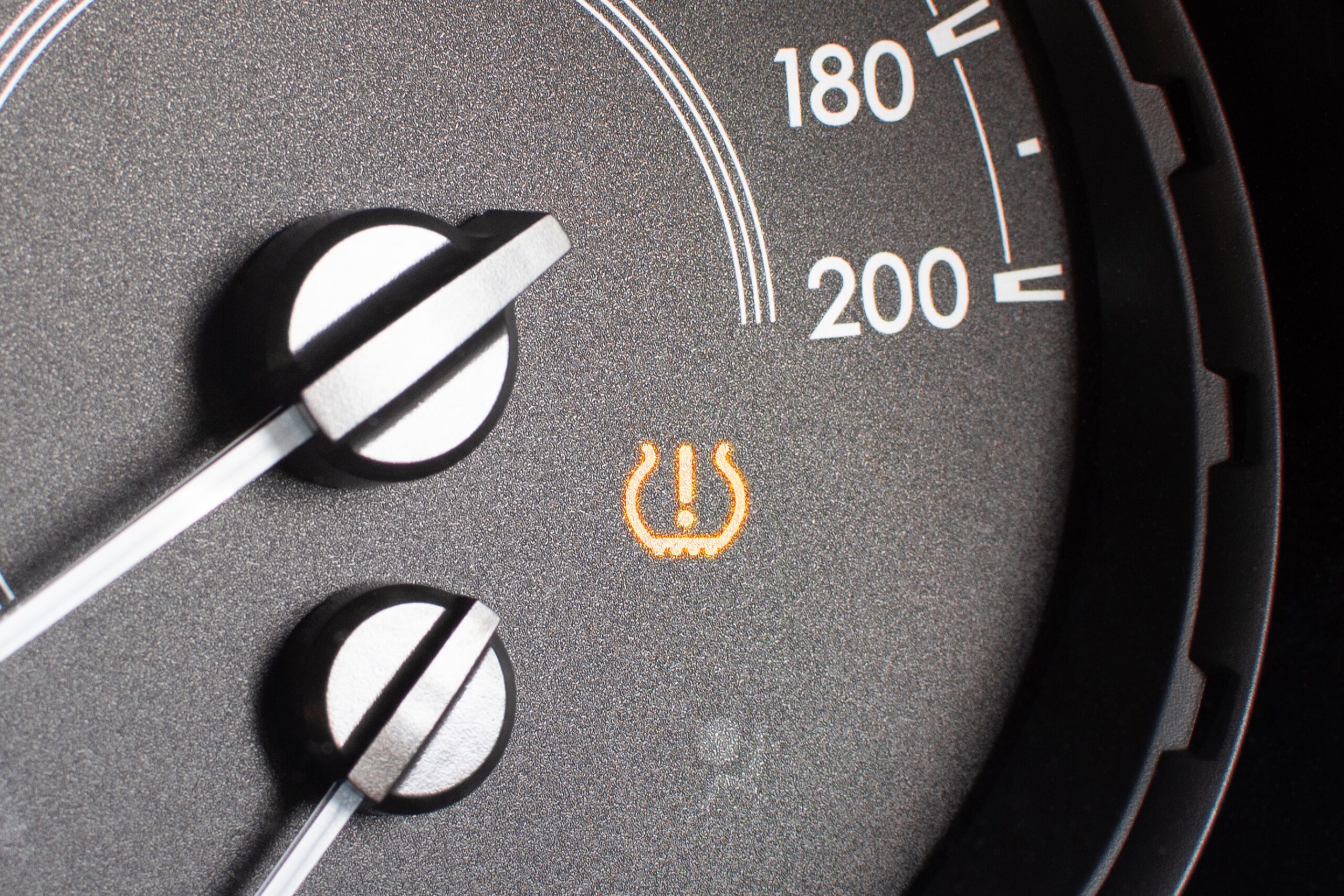 Tire pressure warning light on car dashboard as triggered by the TPMS sensor.