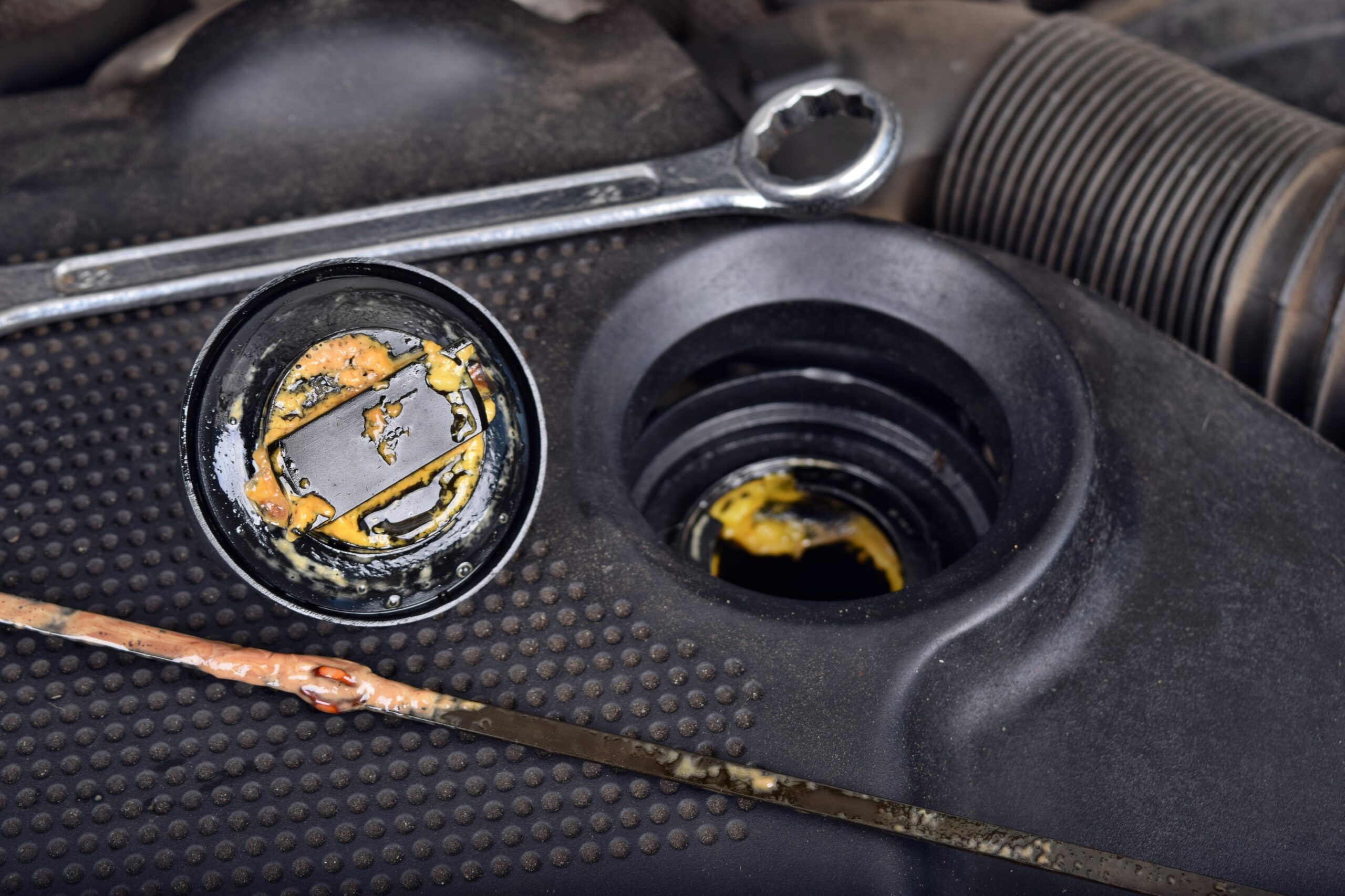 The thick, greasy yellow motor oil under oil cap as signs and symptom of a blown head gasket. Broken a car