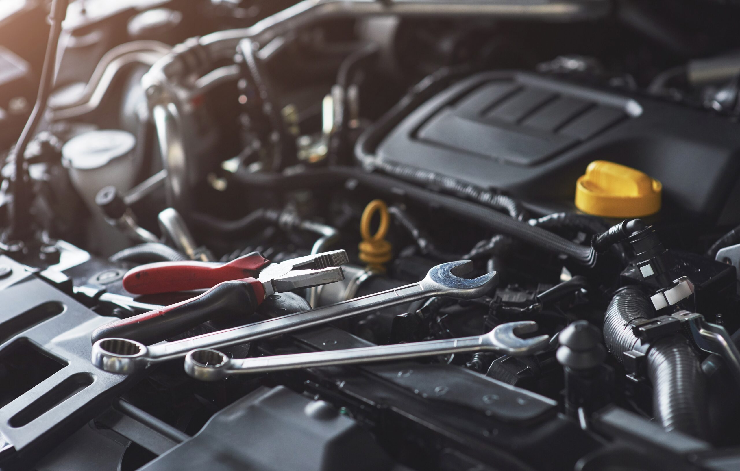 Several tools lying on top of a vehicle engine, ready for routine maintenance.
