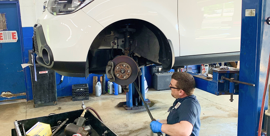 Telle Tire technician working on the brake system of a vehicle on a lift in the garage.
