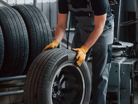 A Telle tire technician rolling a mounted tire off the rack in the shop.